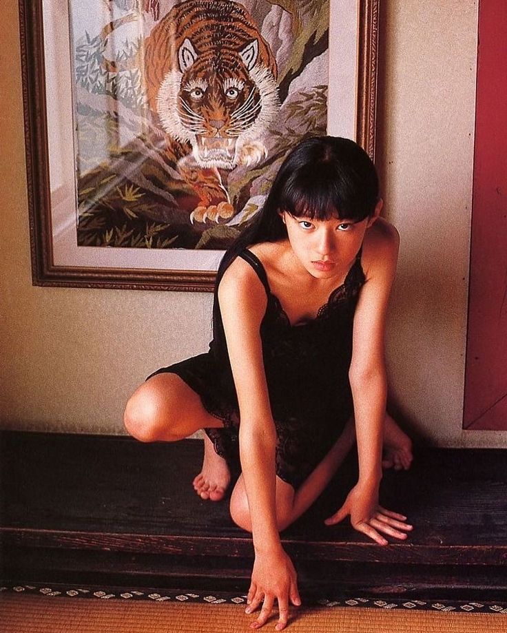 a woman sitting on the floor in front of a painting with a tiger behind her