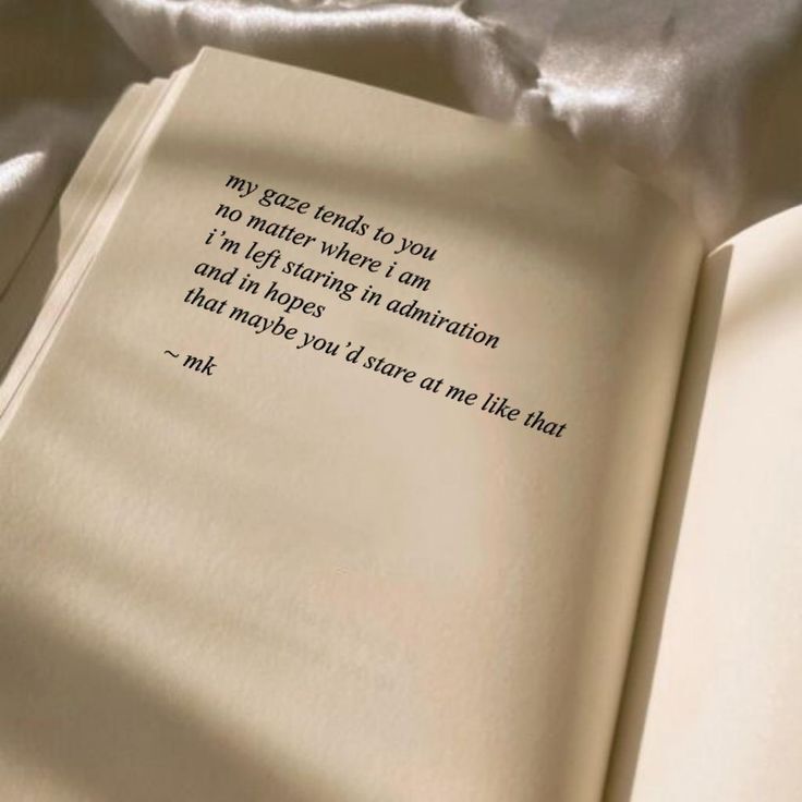 an open book sitting on top of a bed covered in white sheets with a poem