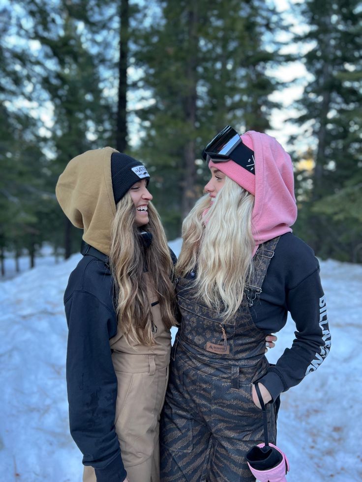 two women standing next to each other in the snow