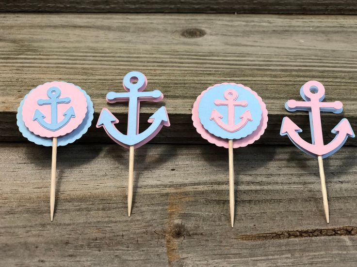 three cupcake toppers with pink and blue anchors on them