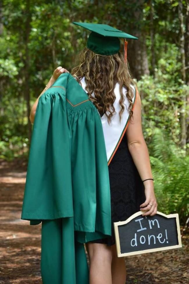 a woman wearing a graduation gown and holding a chalkboard