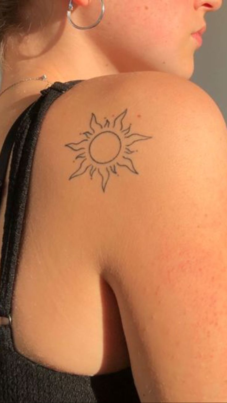 a woman with a sun tattoo on her shoulder