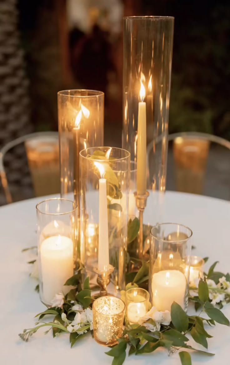 candles and greenery are arranged on a table