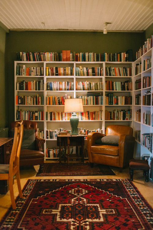 a living room filled with furniture and lots of bookshelves next to a table