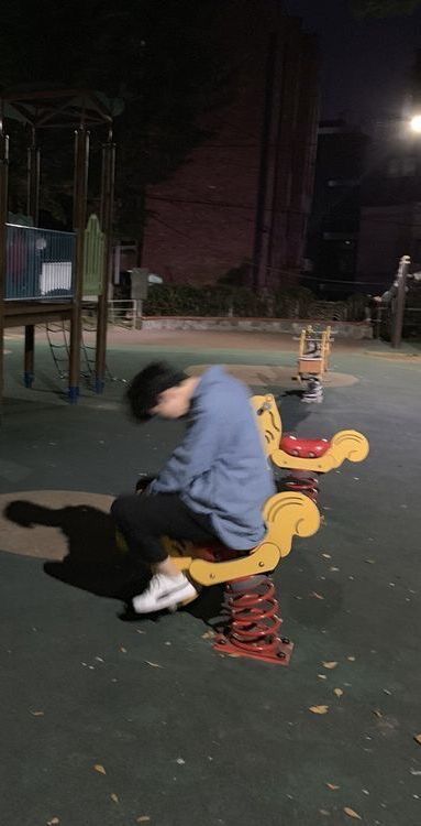 a man sitting on top of a yellow bench next to a playground area at night