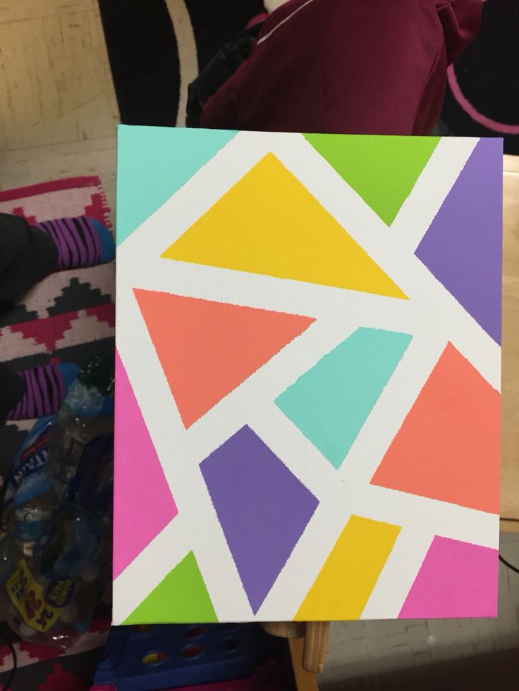 a person holding up a piece of art that has been painted with different colors and shapes