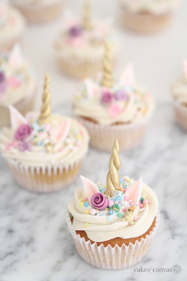 cupcakes decorated with white frosting and pink flowers are sitting on a marble table