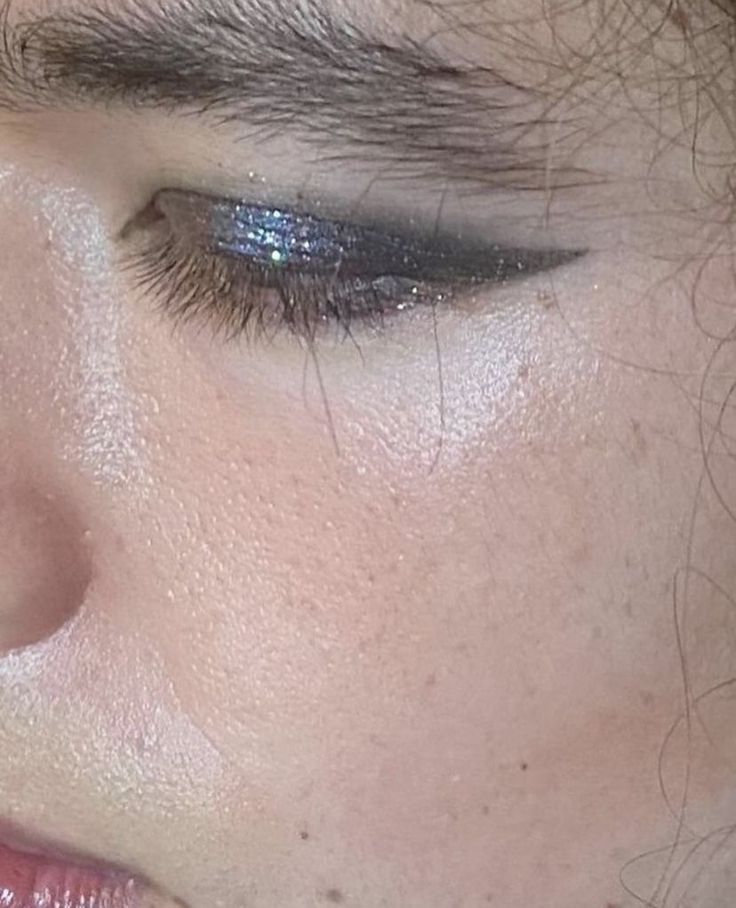 a close up of a woman's face with blue and silver eyeliners