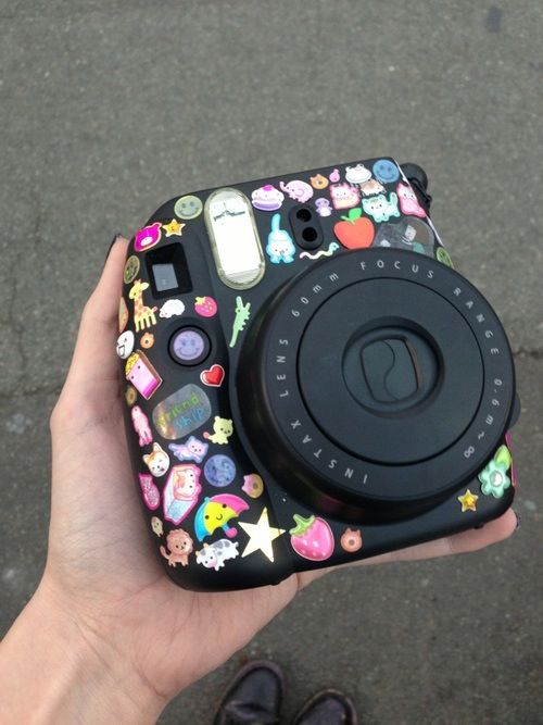 a person holding up a camera with stickers on it