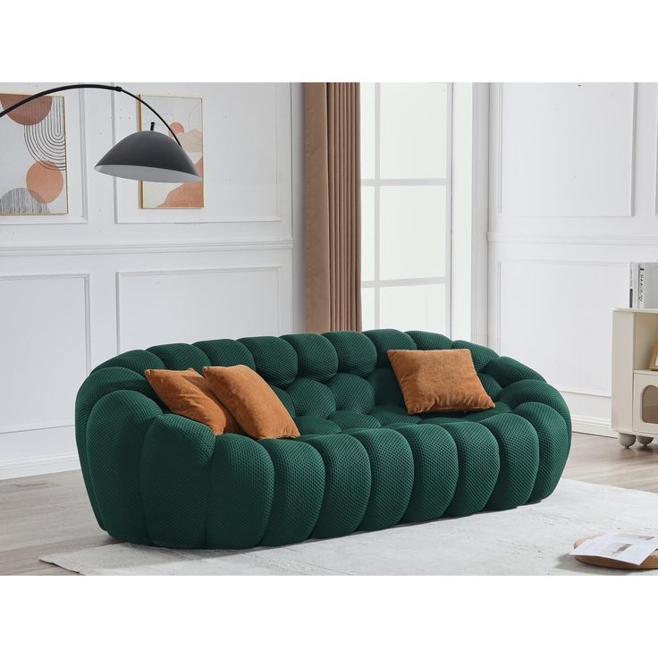 a green couch sitting on top of a white rug in a living room next to a lamp