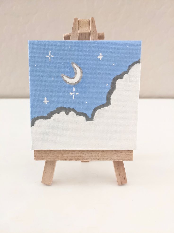 an easel with a painting on it and a moon in the sky behind it