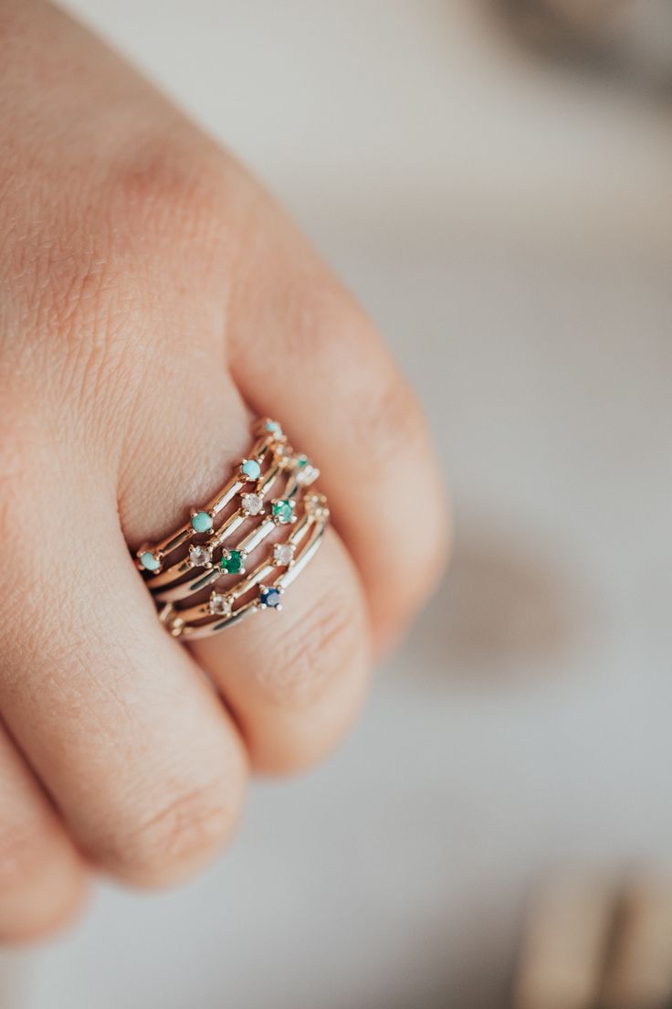 a woman's hand with a stack of rings on top of her ring finger