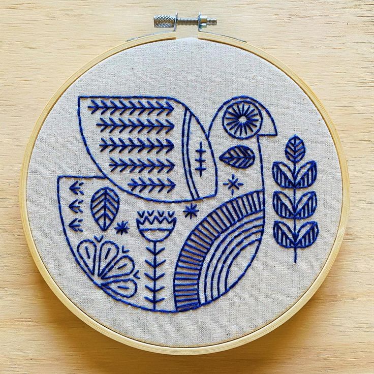 a blue and white embroidered bird sitting on top of a wooden table