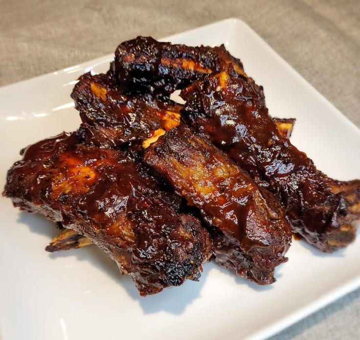 some ribs are on a white plate with sauce