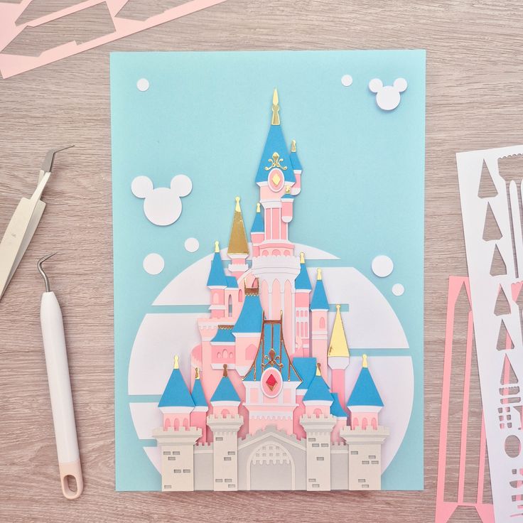 a paper cut out of a castle on top of a table next to scissors and glue