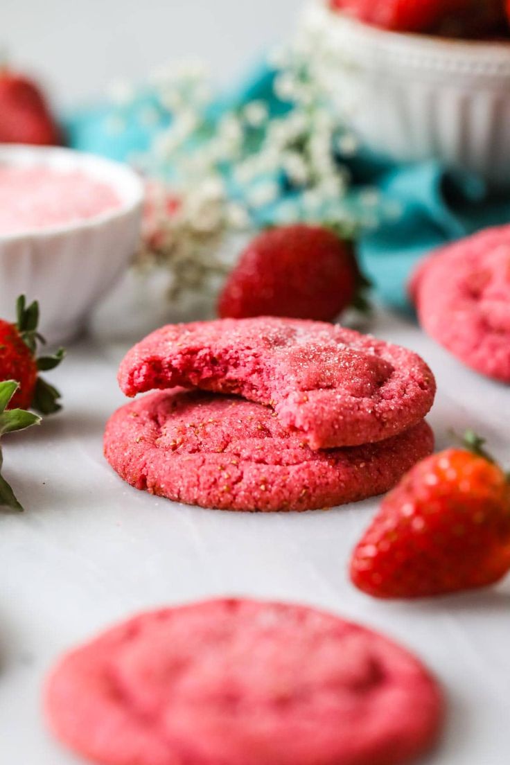 strawberry cookies with powdered sugar and fresh strawberries on the table next to them