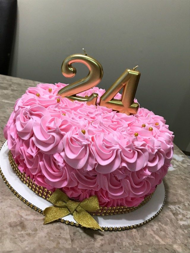 a birthday cake with pink frosting and gold numbers on top, sitting on a table