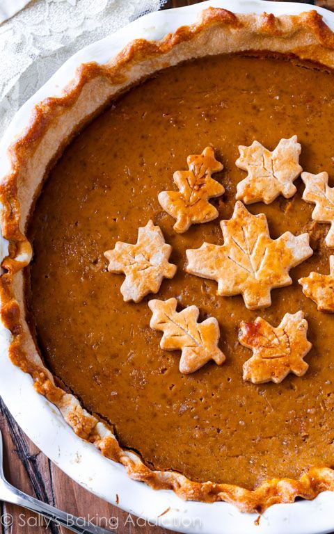 a pie is decorated with small leaves and snowflakes on the top, sitting on a wooden table