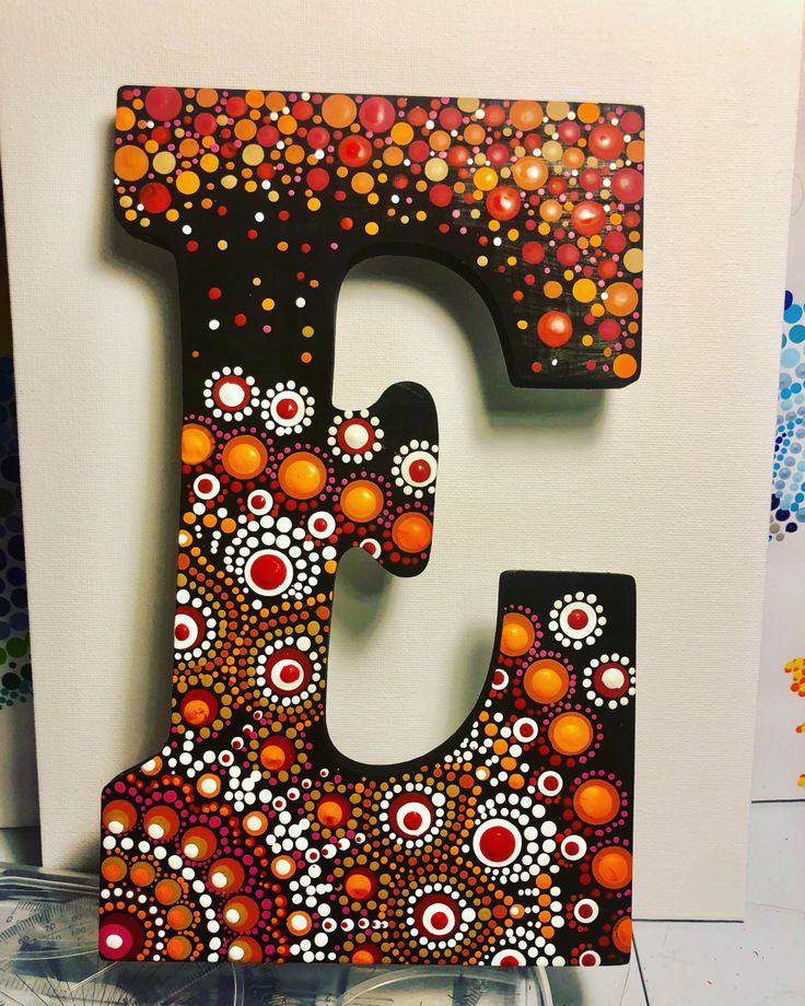 the letter e is painted with colorful dots and circles on it's black frame