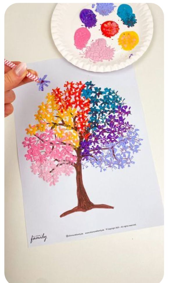 a child's hand is holding a paper plate with an image of a tree on it