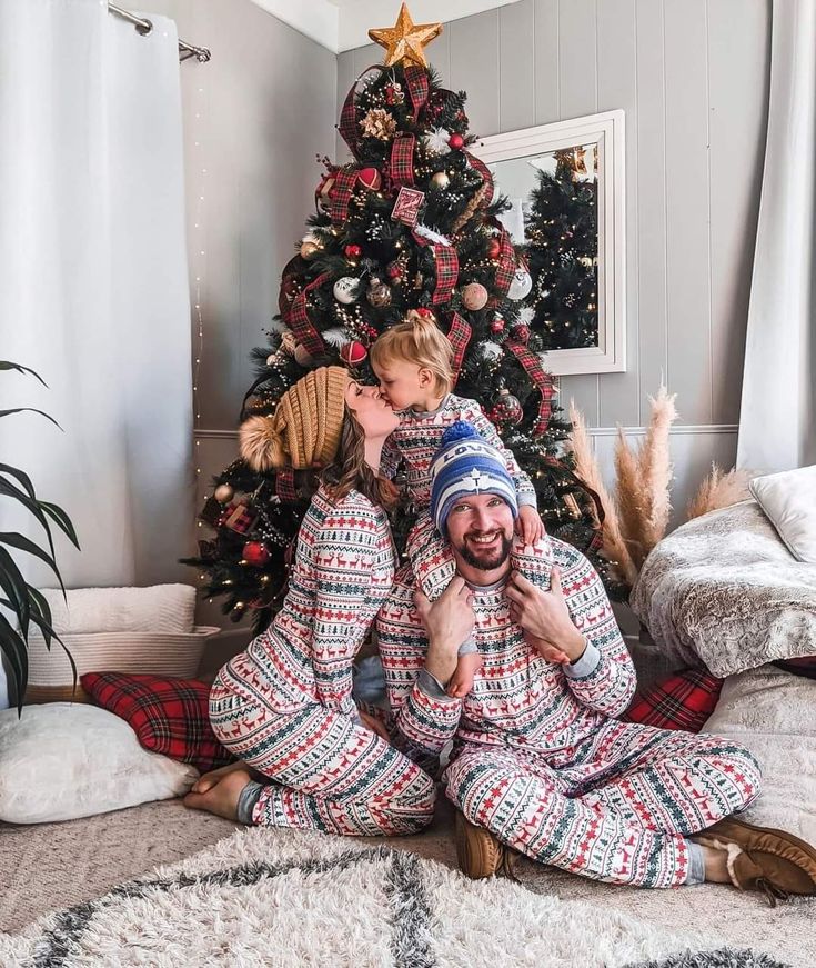 a man and child sitting in front of a christmas tree