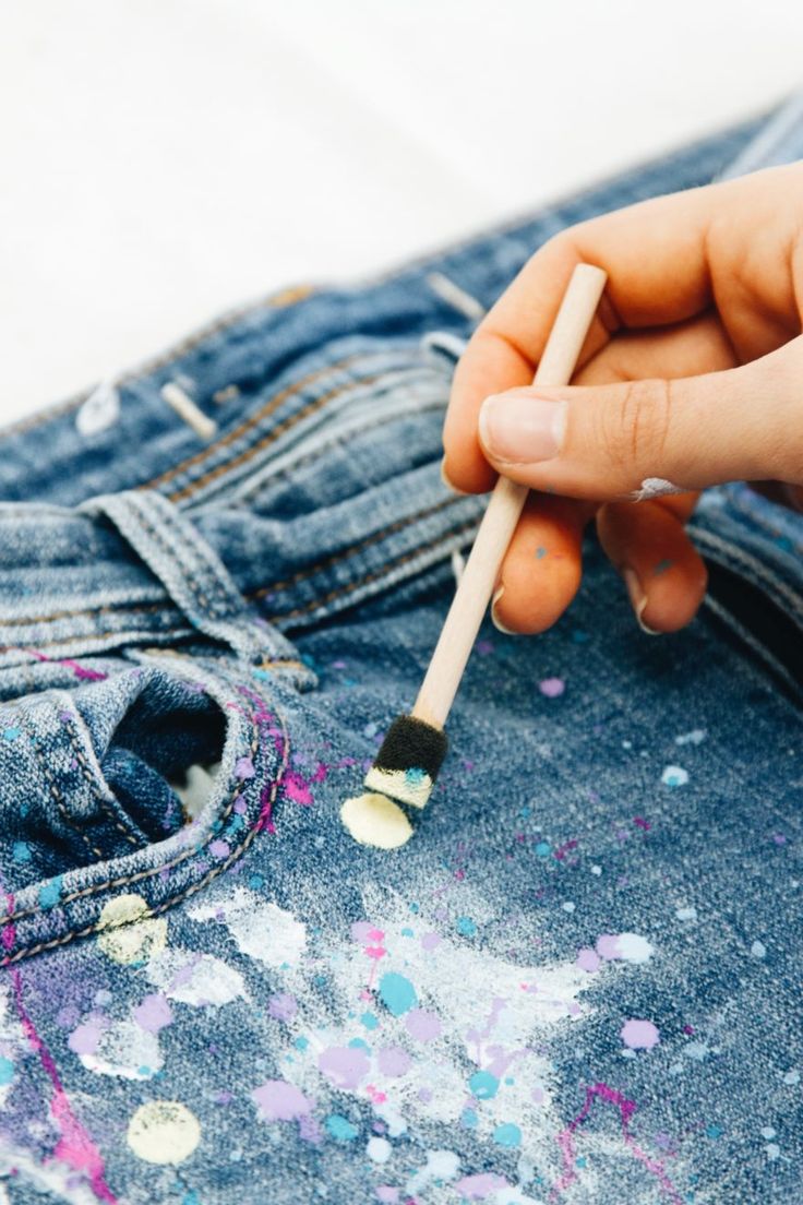 a person holding a paintbrush in their left hand while sitting on the back of a pair of jeans