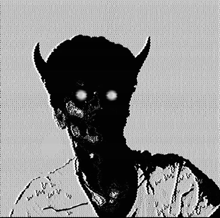 a black and white photo of a person wearing a devil mask with glowing eyes on their face