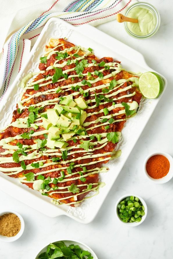 an enchilada covered in sauce, avocado and cilantro