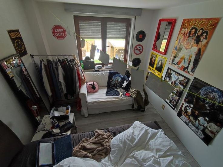 the room is cluttered with clothes and posters