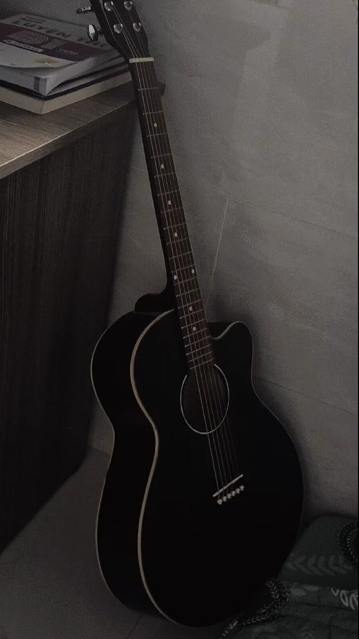 a black acoustic guitar sitting on top of a table