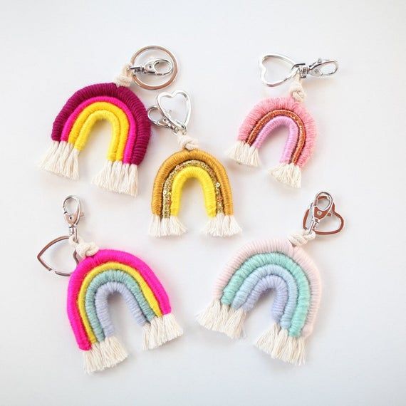 four rainbow key chains with tassels hanging from each one on a white background