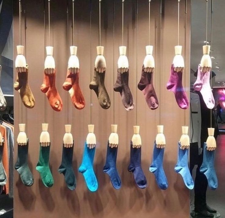 there are many pairs of socks hanging on the wall in this store display case,