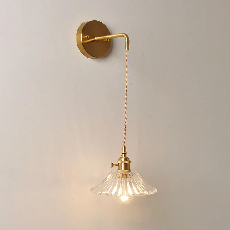 a wall light with a glass shade hanging from it's side on a white wall