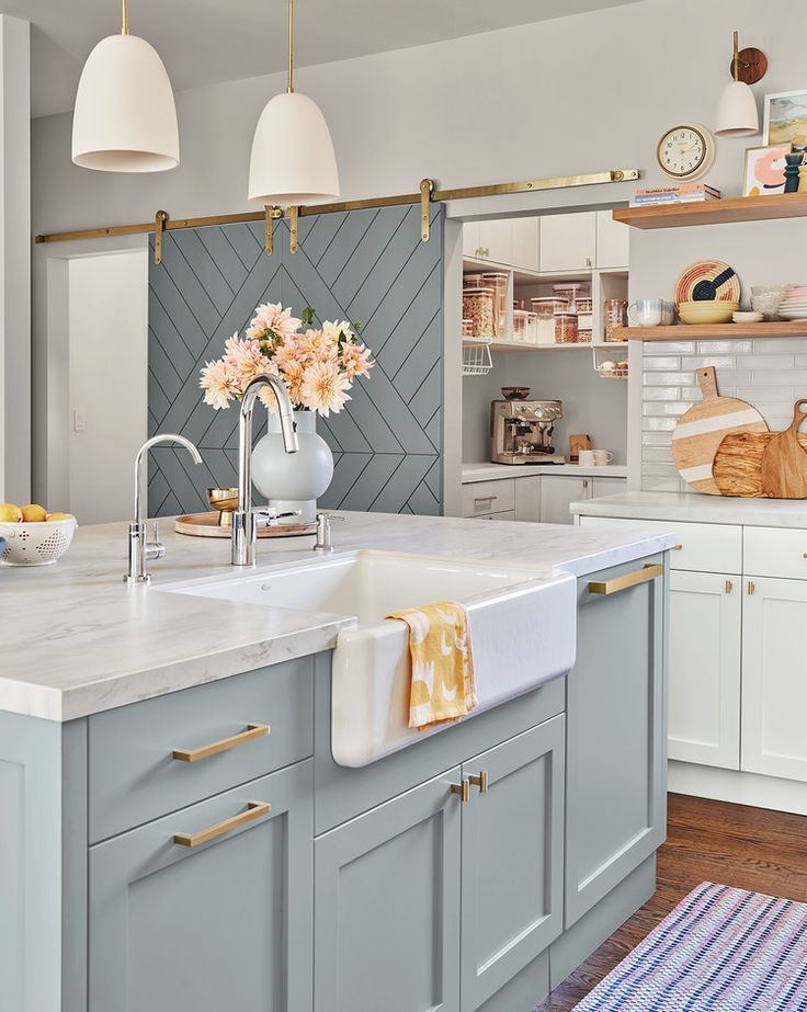 a kitchen with blue cabinets, white counter tops and yellow accents on the wall above the sink