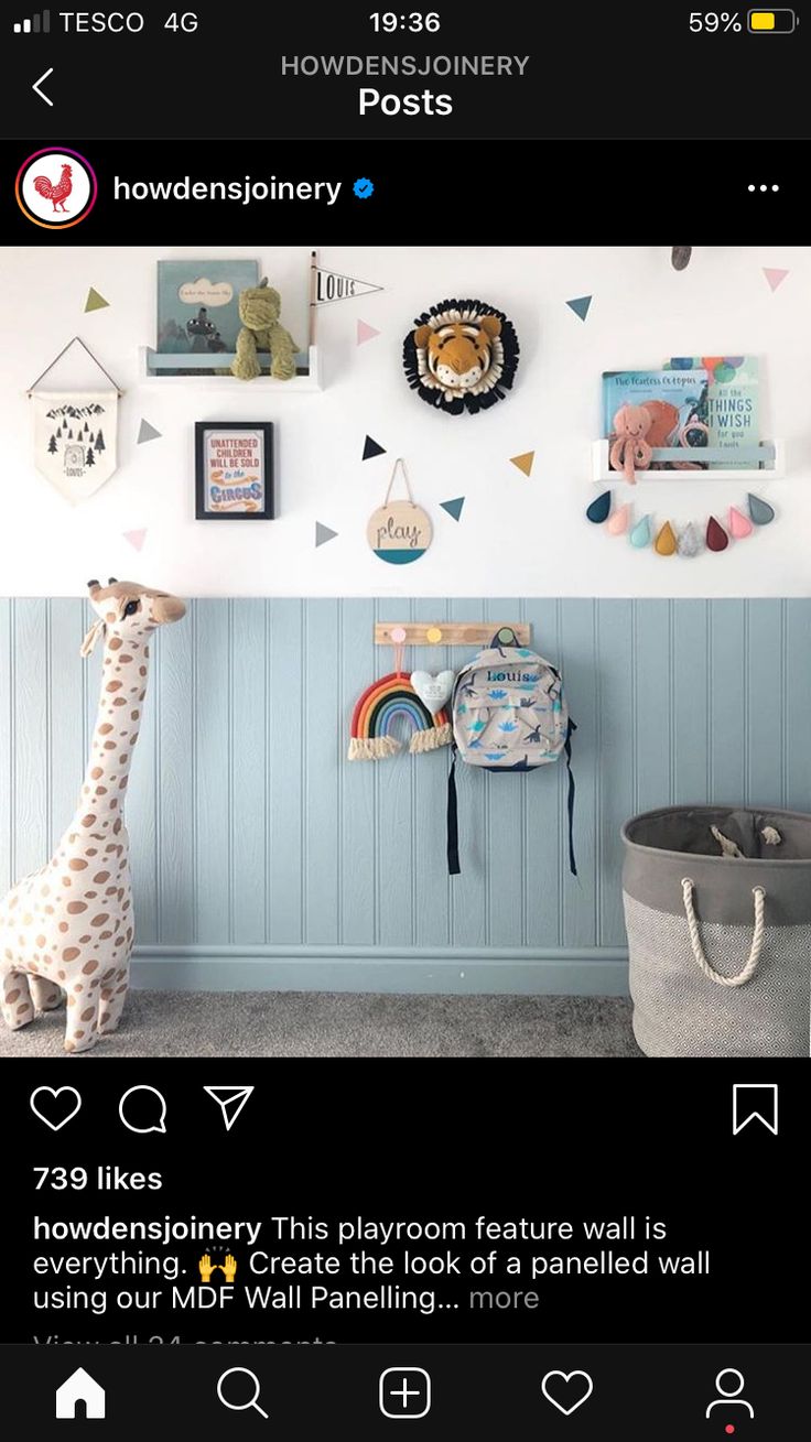 a giraffe is standing in front of a wall with pictures and other items on it