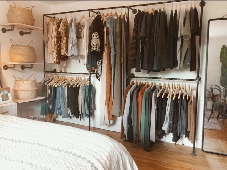 a bedroom with clothes hanging on the wall and a bed in front of an open closet