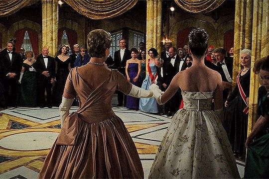 two women in formal dresses are shaking hands