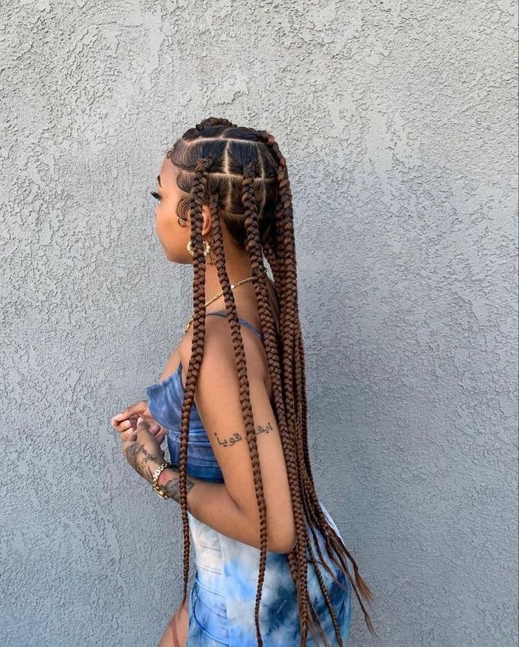 a woman with long braids standing in front of a wall