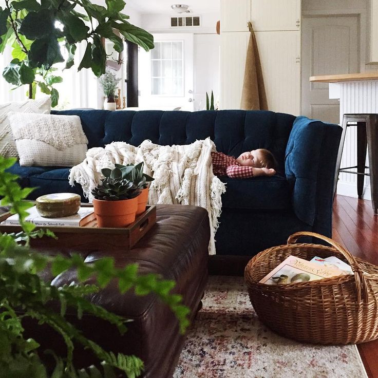 a woman laying on top of a blue couch in a living room