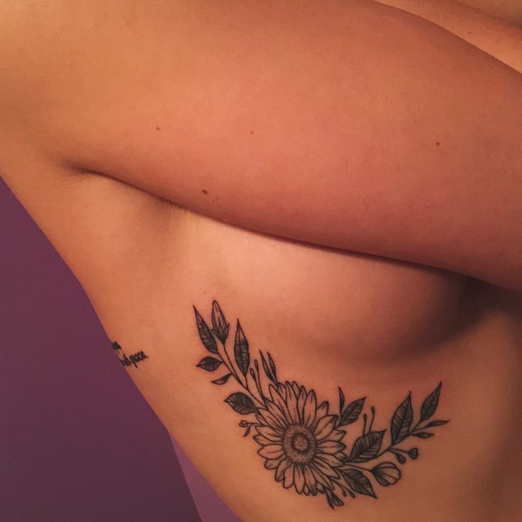 a woman's breast with flowers and leaves tattooed on the side by her arm