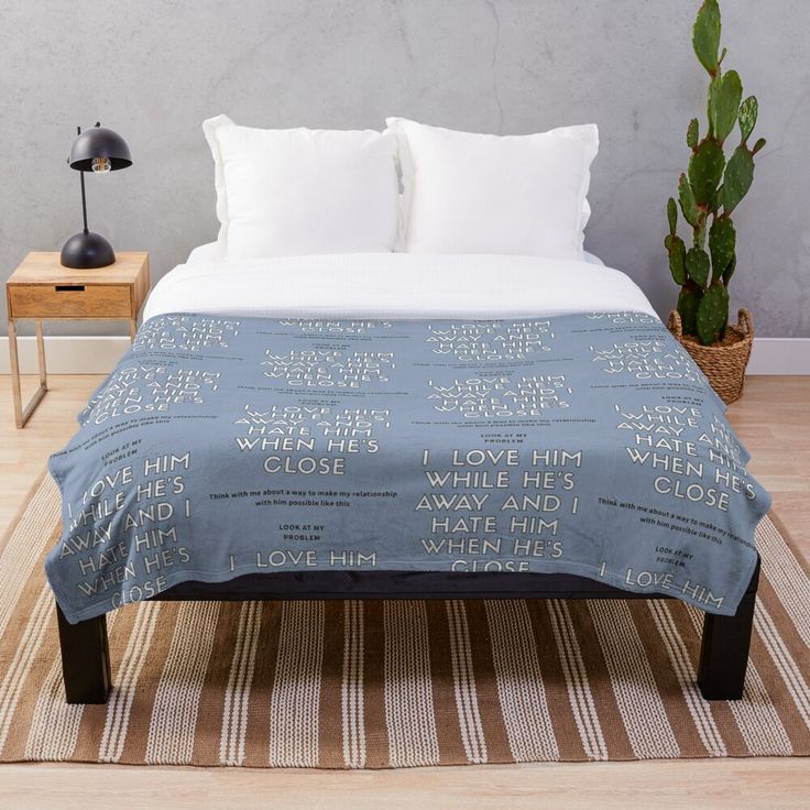 a bed with a blue blanket on top of it next to a potted plant