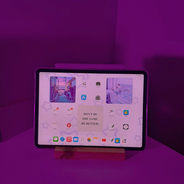 a tablet computer sitting on top of a wooden stand in front of a purple wall