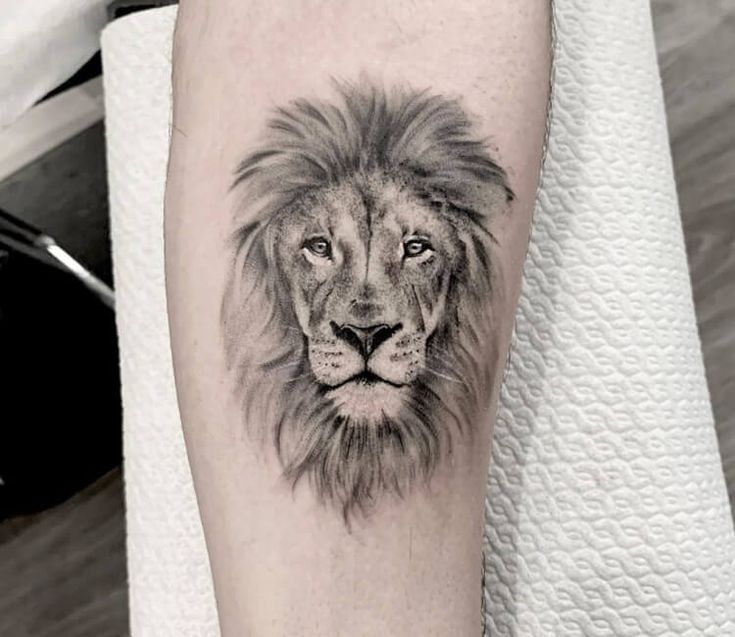 a black and white photo of a lion's face on the left forearm tattoo