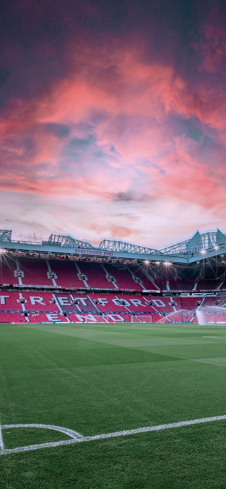 an empty soccer stadium with red and white lights on the stands at sunset or dawn