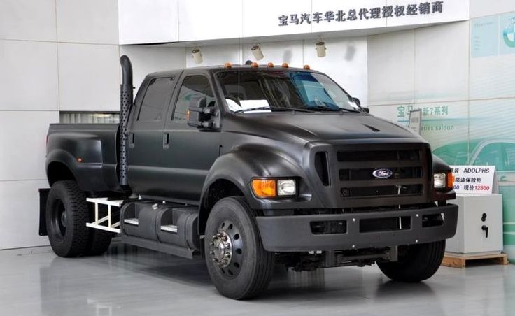 a large black truck parked in a garage next to a white wall with chinese writing on it