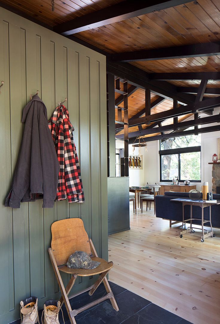 a chair and coat rack in a room with wood floors, green walls and wooden ceiling