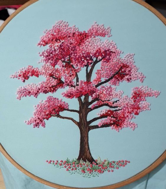 a pink tree painted on a light blue wall hanging in front of a wooden frame