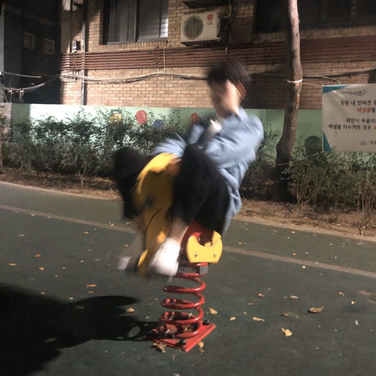 a person riding a toy on top of a wooden pole in the street at night