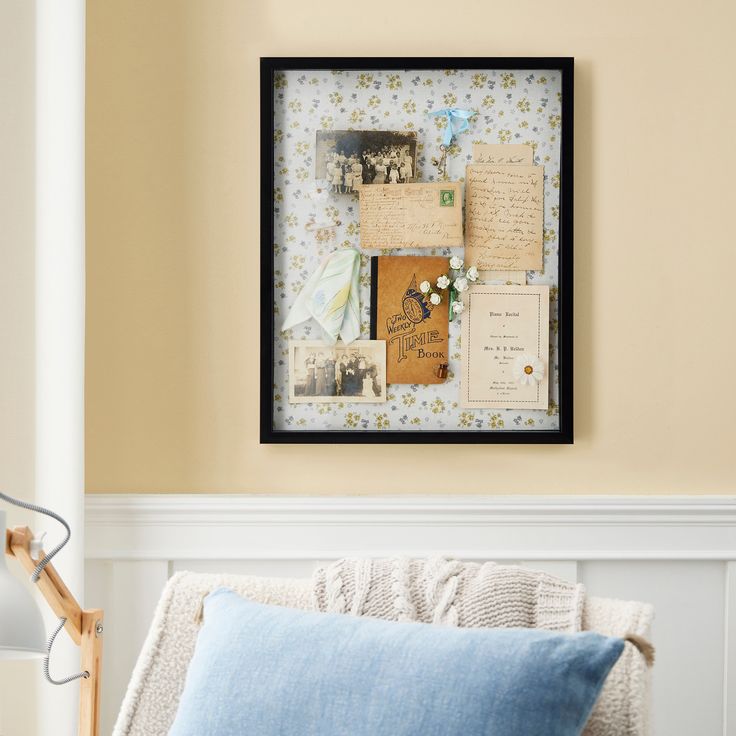 a bed with a blue pillow on top of it next to a framed photo and papers