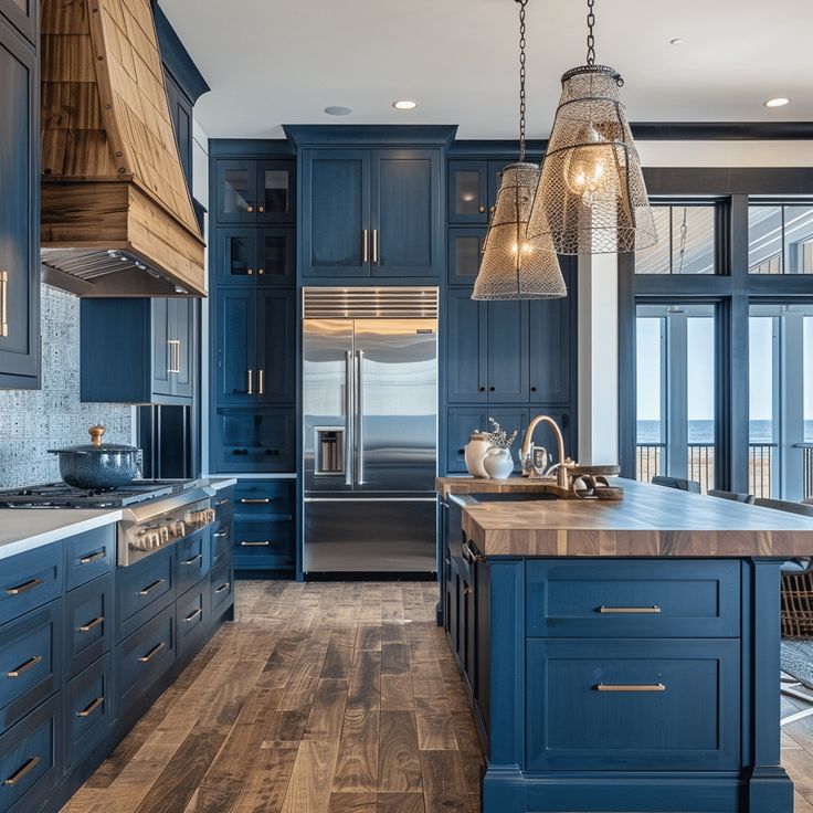 a large kitchen with blue cabinets and wooden flooring next to an ocean view window